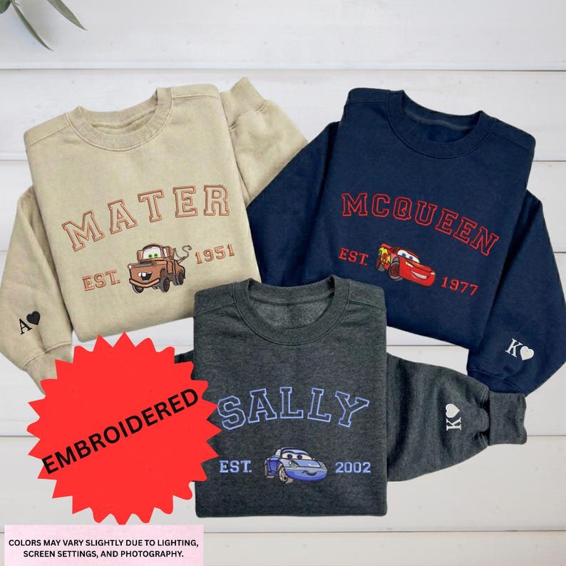 a collection of four children's sweatshirts, each featuring a different character from the Disney animated film "Cars". The sweatshirts are arranged on a white background, showcasing the various designs and colors.