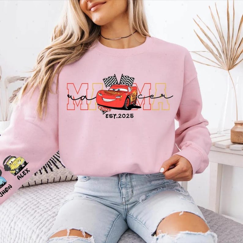 A woman wearing a pink sweatshirt with a graphic of a red car and the text "Mama" on it.