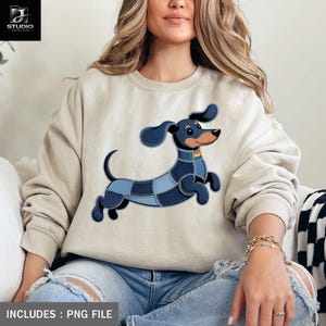 Pode incluir: Camisola bege com um cão dachshund de desenho animado com um design de retalhos de ganga. O cão tem orelhas azuis, corpo preto e uma coleira arco-íris. O texto "INCLUDES: PNG FILE" está na parte inferior.