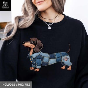 Könnte beinhalten: Schwarzes Sweatshirt mit einem Cartoon-Dackel in einem Jeans-Patchwork-Outfit. Der Hund hat braunes und hellbraunes Fell und einen Pfotenabdruck auf seinem Bein. Der Text "INCLUDES : PNG FILE" befindet sich unten.