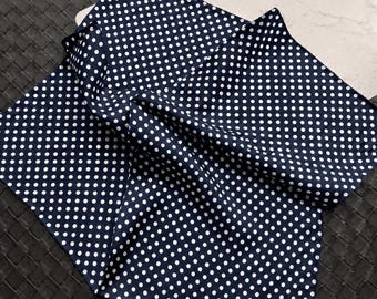 May include: Navy blue pocket square with a white polka dot pattern. The square is folded and draped, showing the fabric's texture. The classic design is suitable for formal or casual wear.