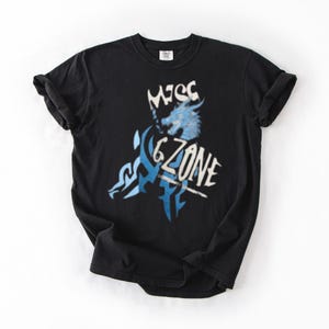 May include: Black t-shirt with a distressed graphic design. The design features the text "MESS 6 ZONE" in white and blue, along with a stylized wolf or dragon illustration. The shirt has short sleeves and a crew neck.
