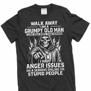 Op de afbeelding: Zwart t-shirt met witte tekst en een afbeelding van een skelet met capuchon. De tekst luidt: "WALK AWAY I AM A GRUMPY OLD MAN I LOVE DOGS MORE THAN HUMANS I HAVE ANGER ISSUES AND A SERIOUS DISLIKE FOR STUPID PEOPLE."