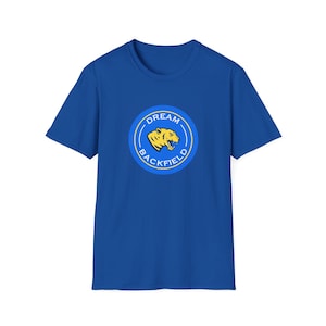 May include: Royal blue t-shirt with a circular graphic. The graphic features a yellow tiger head and the words "DREAM BACKFIELD" in a blue and yellow design. The shirt is made of a soft material.