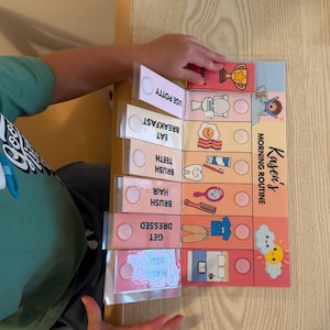 May include: A Kasen's Morning Routine chart featuring colorful illustrations for daily tasks including using the potty, eating breakfast, brushing teeth, brushing hair, and getting dressed, with interactive flaps and circular velcro attachment points.