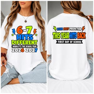 May include: A white t-shirt featuring colorful graphic text. The front displays 6-7 HITS DIFFERENT WHEN IT'S THE SCHOOL YEAR 2026 2027. The back shows 2026 2027 PREDICTION THIS YEAR HITS BACK FIRST DAY OF SCHOOL with lightning bolt and star accents.
