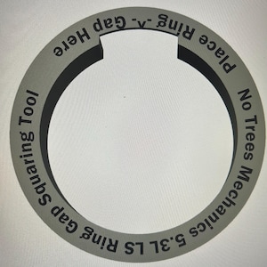 May include: A gray ring gap squaring tool with the text "5.3L LS Ring Gap Squaring Tool", "No Trees Mechanics", and "Place Ring ^. Gap Here". The tool has a circular design with a gap.