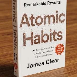 May include: A hardcover book titled "Atomic Habits" by James Clear. The book has a white cover with brown text, including the title and the phrase "Tiny Changes, Remarkable Results." A red sticker indicates over 1 million copies sold.