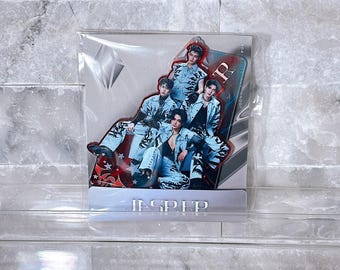 May include: A clear plastic-wrapped, die-cut acrylic stand featuring a group of five people in denim outfits. The stand has a red and silver design with the word "JASPER" at the base. The background is a light gray brick wall.