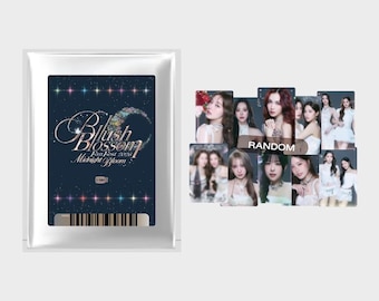 May include: A rectangular white foil packet featuring a dark blue label with the text Blush Blossom Fan Fest 2026 Midnight Bloom and a barcode. Beside it are several rectangular photo cards displaying portraits of various individuals in white outfits.