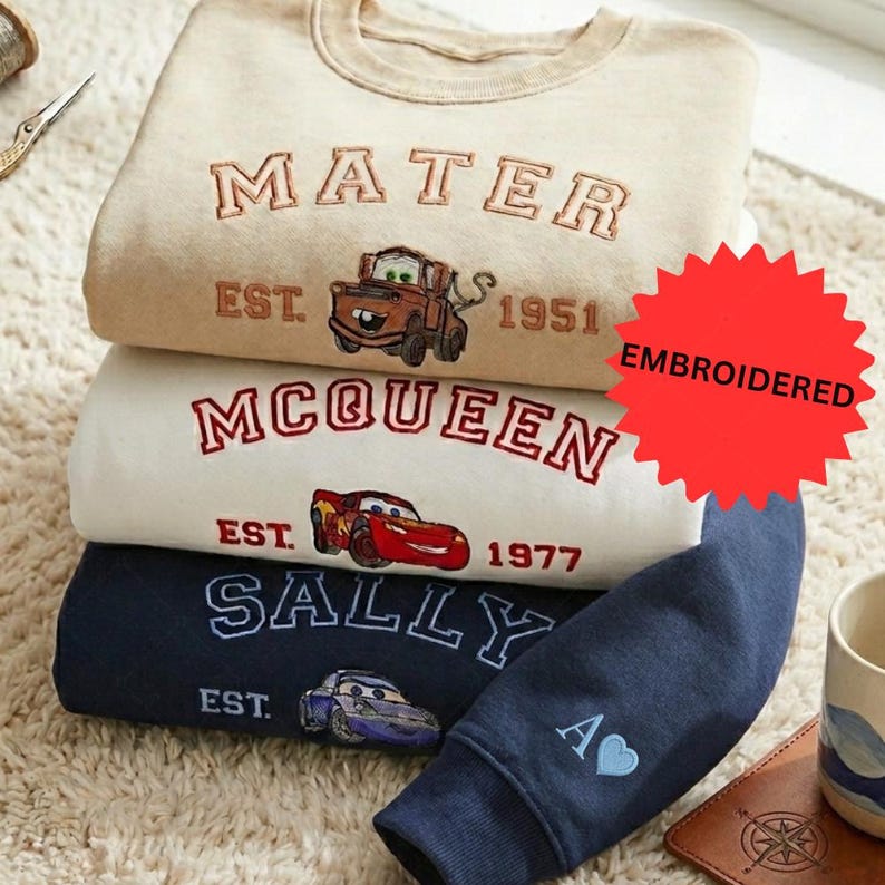 a stack of three sweatshirts with various Disney character designs, including a character from the Cars movie franchise.
