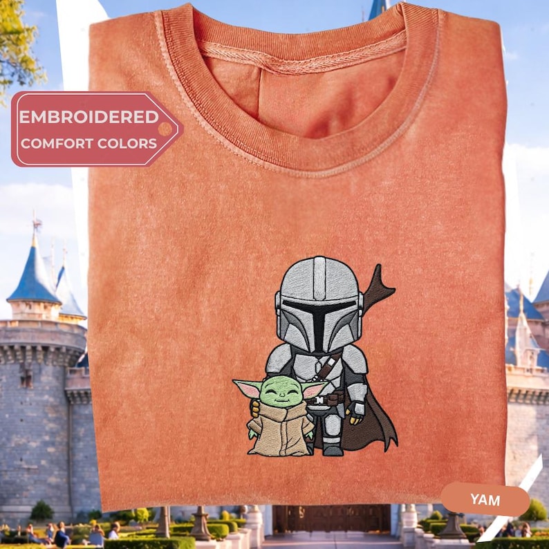 a red t-shirt with a graphic of a character and a child, likely representing the Mandalorian family from the Star Wars franchise.