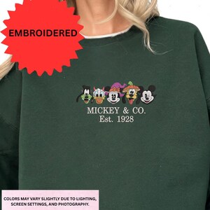 A green sweatshirt with a red starburst and an embroidered design featuring the characters Mickey Mouse and Co.