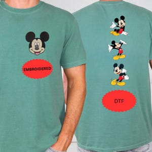 a green t-shirt with a Mickey Mouse design and the text "EMROIDED" and "DFT" printed on it.