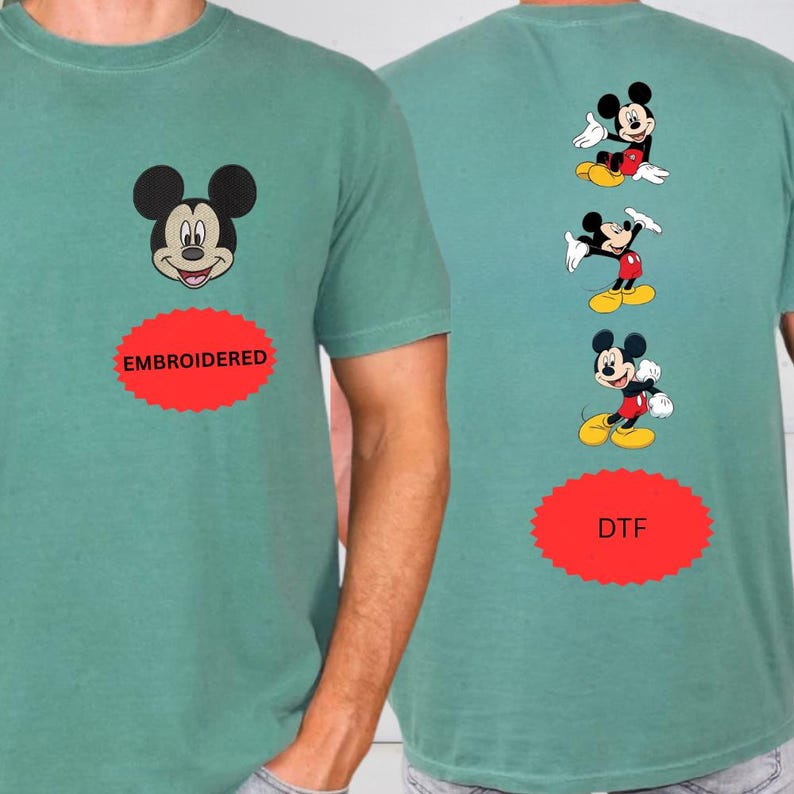 a green t-shirt with a Mickey Mouse design and the text "EMROIDED" and "DFT" printed on it.