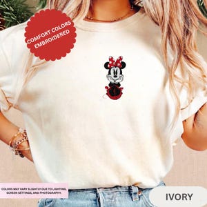 A person wearing a white t-shirt with a Minnie Mouse embroidered on it.