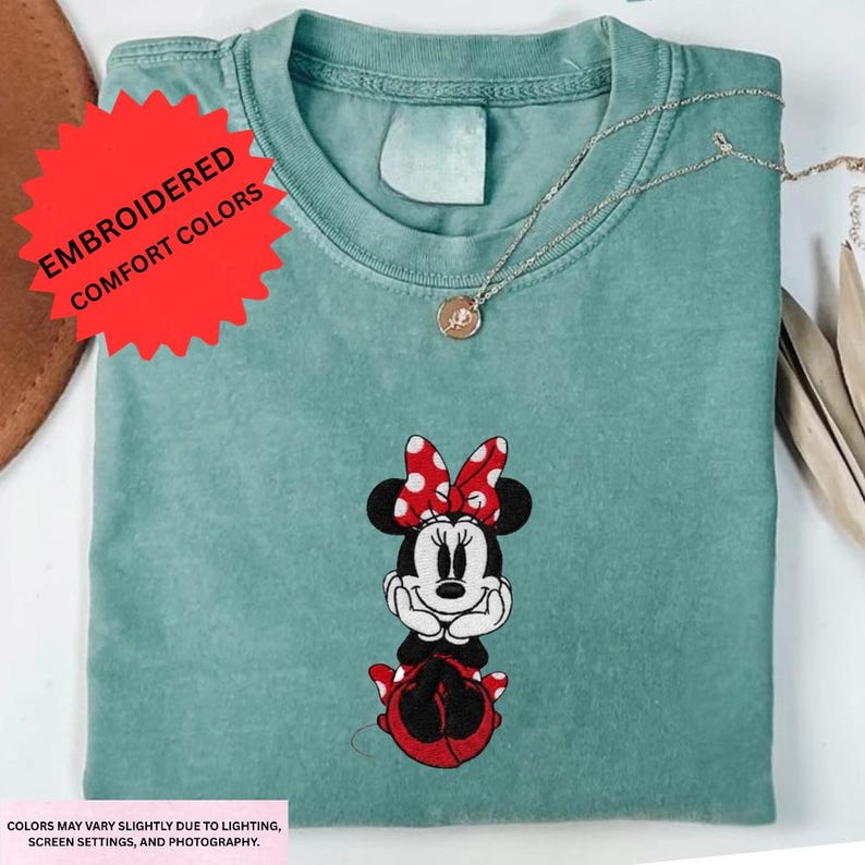 a green t-shirt with a Minnie Mouse embroidered design on it, along with a necklace and some other accessories.
