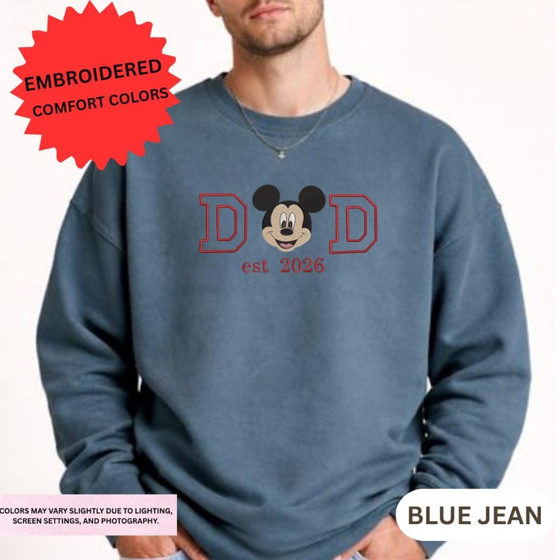 A man wearing a blue sweatshirt with a Mickey Mouse design and text printed on it.