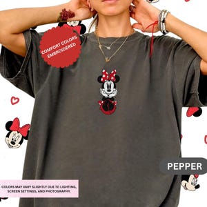 A person wearing a gray t-shirt with a Minnie Mouse embroidered design, surrounded by Minnie Mouse motifs.
