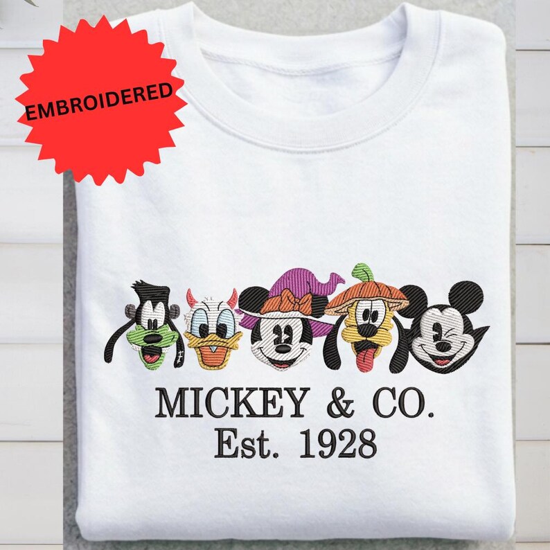A white t-shirt with a red starburst logo and a line of colorful Mickey Mouse characters, along with the text "MICKEY & CO. Est. 1928".