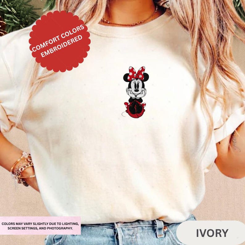 A person wearing a white t-shirt with a Minnie Mouse embroidered on it.