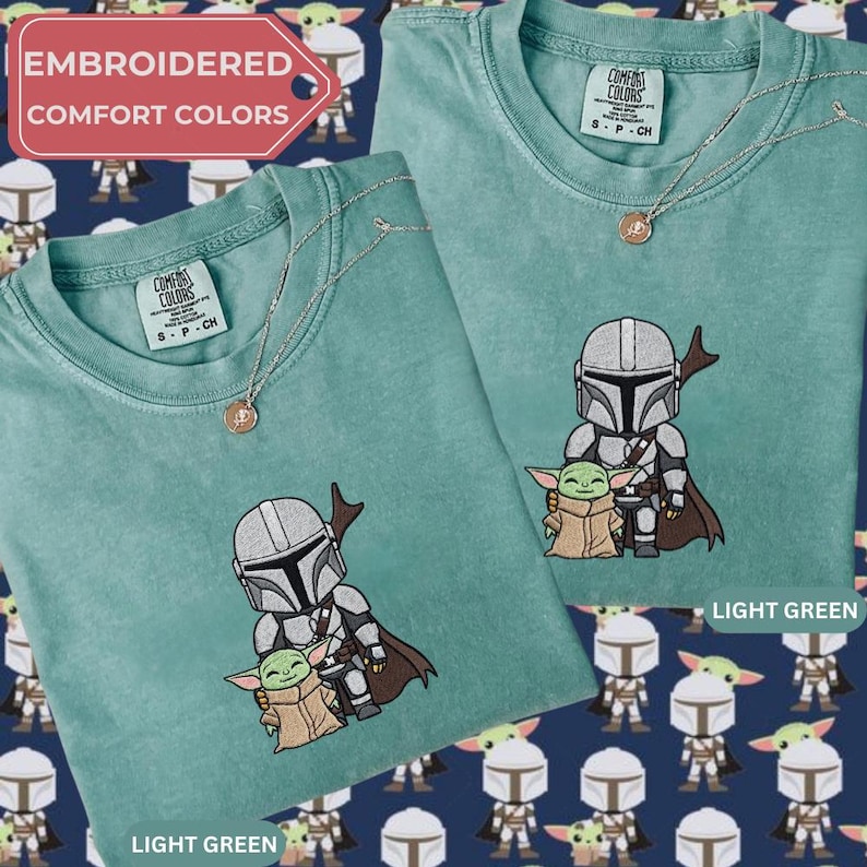 Embroidered comfort colors t-shirt with a character from the Star Wars franchise, including a baby Yoda, displayed on a light green background.