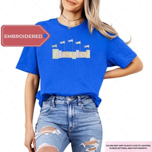 A woman wearing a blue t-shirt with the word "Disneyland" printed on it, paired with distressed jeans.
