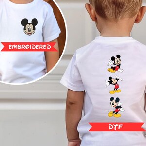 a child wearing a white t-shirt with a Mickey Mouse embroidered design on the back.