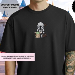 A black t-shirt with a graphic design depicting a character and a smaller character, likely representing the Star Wars universe.