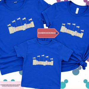 three blue t-shirts with the word "Disneyland" printed on them, along with a red embroidered label that reads "EMBROIDED".