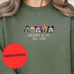 A green sweater with a graphic design featuring the faces of Mickey Mouse and Goofy.