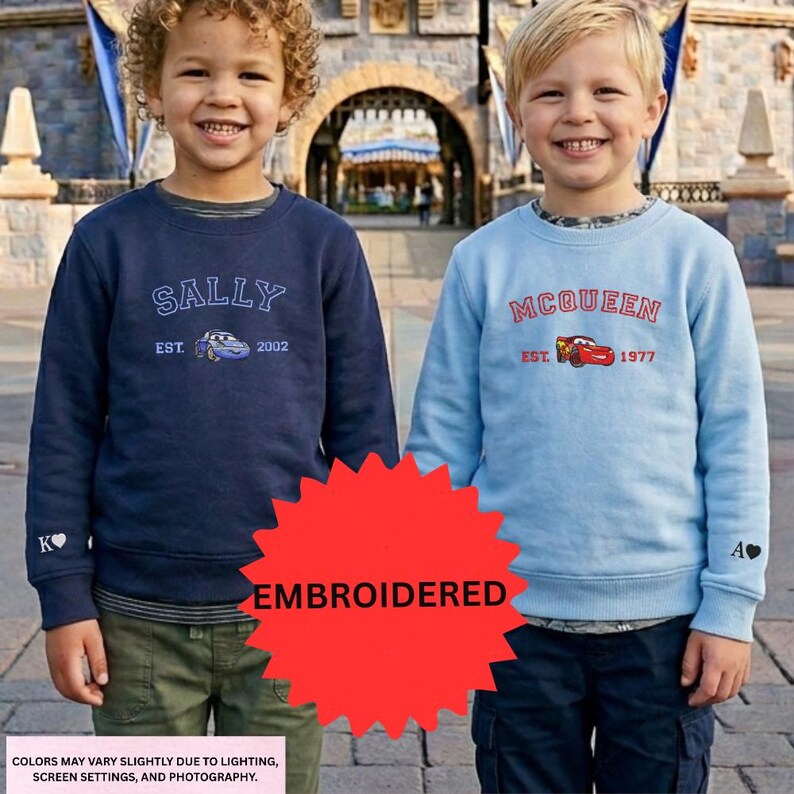 Two young boys wearing sweatshirts with the characters Sally and Queen from the Cars movie, standing in front of a castle-like structure.