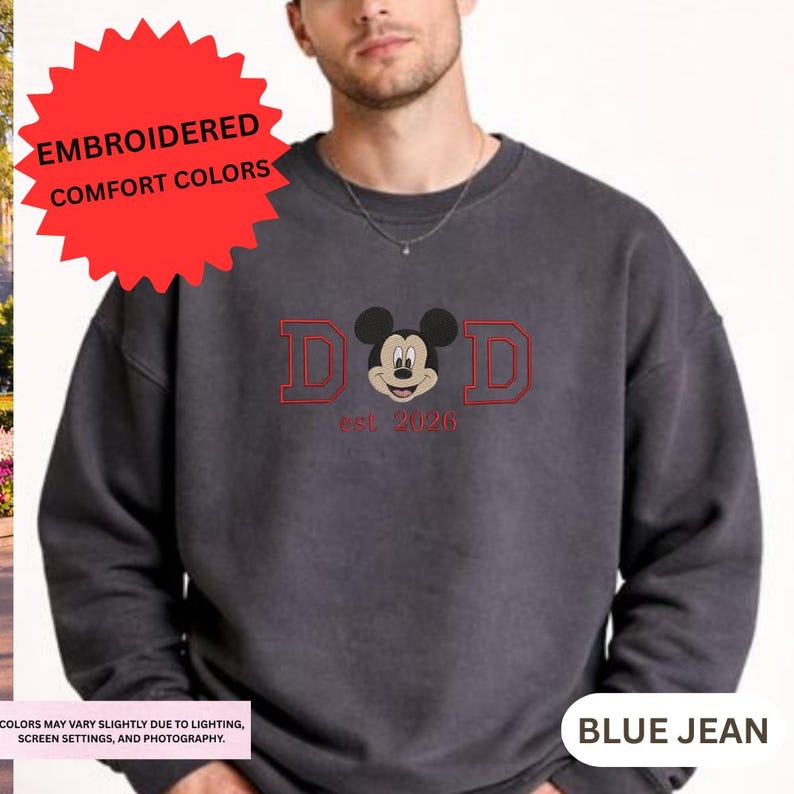 A man wearing a gray sweatshirt with a red and black design featuring a cartoon character and text.