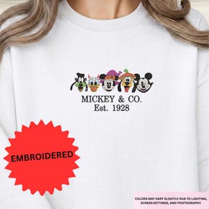 A white t-shirt with a graphic design featuring the characters Mickey Mouse and Co.