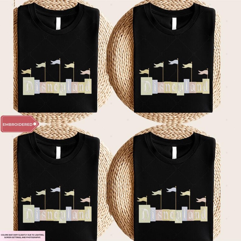 four black t-shirts with the word "Disneyland" printed on them, along with a wicker basket.