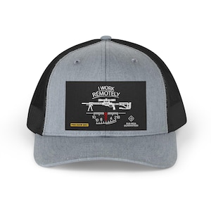 Może przedstawiać: Szara i czarna czapka typu trucker z prostokątną naszywką z grafiką karabinu i napisem "I WORK REMOTELY". Dodatkowy tekst to "PRECISION BRO" i "SUB-MOA GUARANTEED". Czapka ma siatkową tylną część i zakrzywiony daszek.
