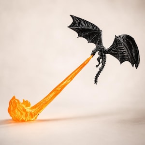 May include: A black dragon figurine in flight with wings spread wide, emitting a long, translucent orange stream of fire that extends downwards to a textured, flame-shaped base, creating a dynamic scene of a creature breathing fire.
