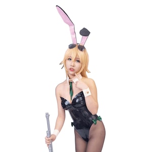 May include: A black and green bunny costume with a matching headband featuring pink and black ears. The costume includes a strapless bodysuit, a green bow, and white cuffs. The person is holding a silver prop.