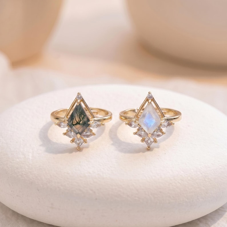 Puede incluir: Dos anillos de oro con engastes de piedras preciosas &uacute;nicos. Uno presenta una piedra de &aacute;gata musgosa verde, el otro una piedra lunar. Ambos anillos tienen un dise&ntilde;o en forma de diamante con peque&ntilde;as piedras de acento claras.