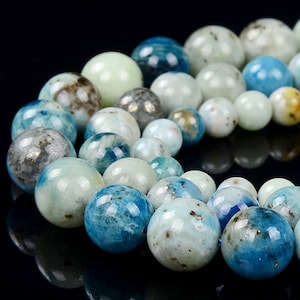 May include: A strand of blue and green gemstone beads. The beads are round and have a speckled appearance.