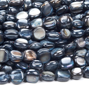 Puede incluir: Una hebra de cuentas de piedras preciosas de color azul oscuro con un acabado liso y pulido. Las cuentas son de forma ovalada y tienen un sutil brillo iridiscente.