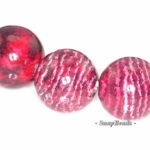 May include: Close-up of a strand of round, red and white patterned beads. The beads have a glossy finish and are strung together on a clear thread.