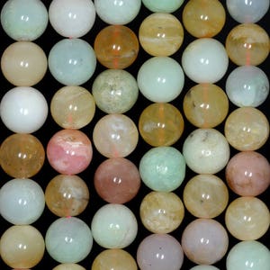 Puede incluir: Una hebra de cuentas redondas y lisas de piedras preciosas en varios tonos de verde, rosa y amarillo. Las cuentas tienen un diámetro aproximado de 10 mm.