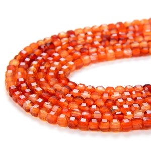May include: A strand of orange carnelian beads, each bead is faceted and has a square shape.