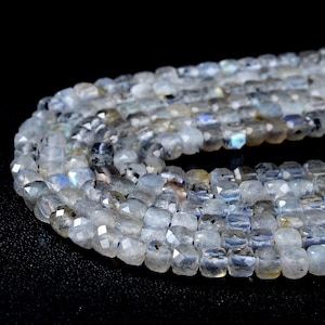 May include: A strand of faceted, light blue labradorite beads. The beads are square-shaped and have a shimmery, iridescent finish.