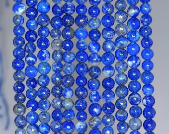 Op de afbeelding: Een streng ronde, blauwe lapis lazuli kralen met vlekken van gouden pyriet. De kralen zijn glad en gepolijst en hebben een licht iriserende glans.