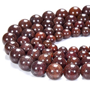 May include: A strand of dark red gemstone beads. The beads are round and have a smooth, polished finish.
