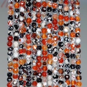 May include: A strand of faceted agate beads in shades of red, white, and black. The beads are approximately 8mm in diameter and have a natural, irregular shape.