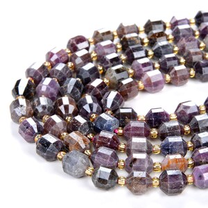 May include: A strand of faceted gemstone beads in shades of purple, blue, and brown. The beads are strung on a gold wire and have a faceted, geometric shape.