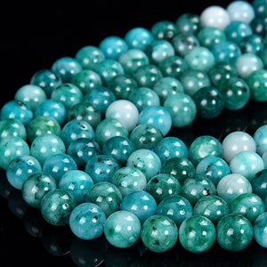May include: A strand of round, teal green gemstone beads. The beads are smooth and polished, with a slight variation in colour.